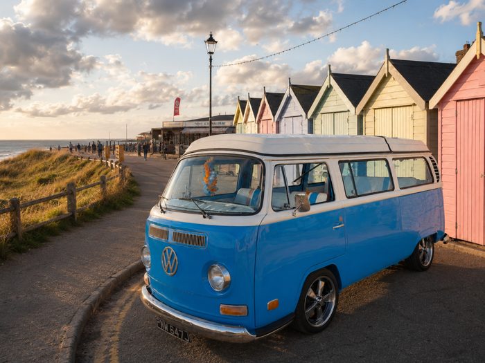 Mabel parked beside colourful beach huts at dusk.