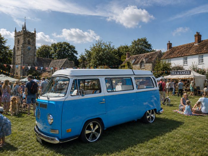 Mabel parked up at a village fete, church tower behind her.