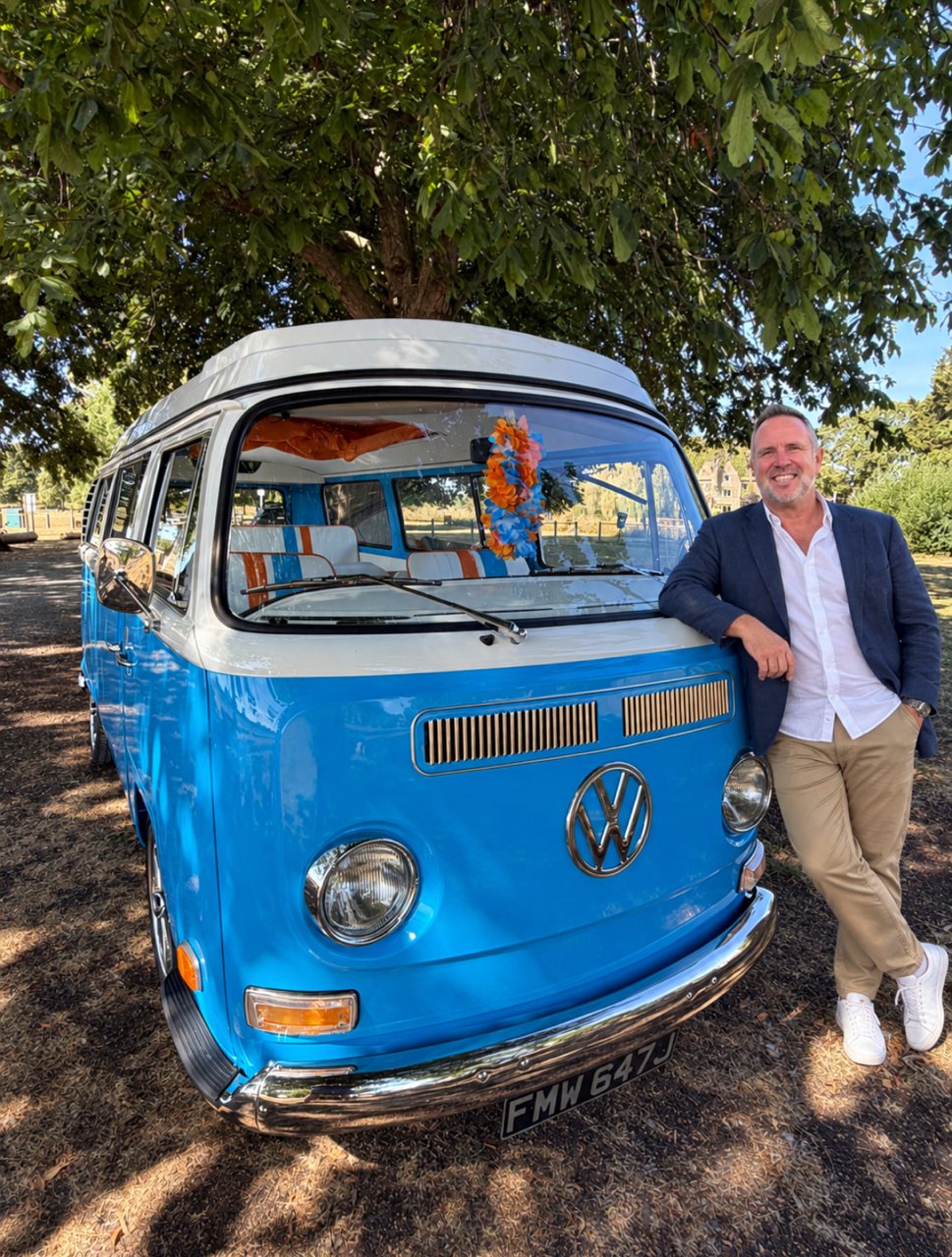 Mark, smiling, leaning on Mabel under a tree.